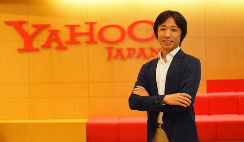ヤフー株式会社 eコマース革命 エバンジェリスト 白山 達也さんがYahoo!Japanのロゴの前で腕を組んで写っているプロフィール写真